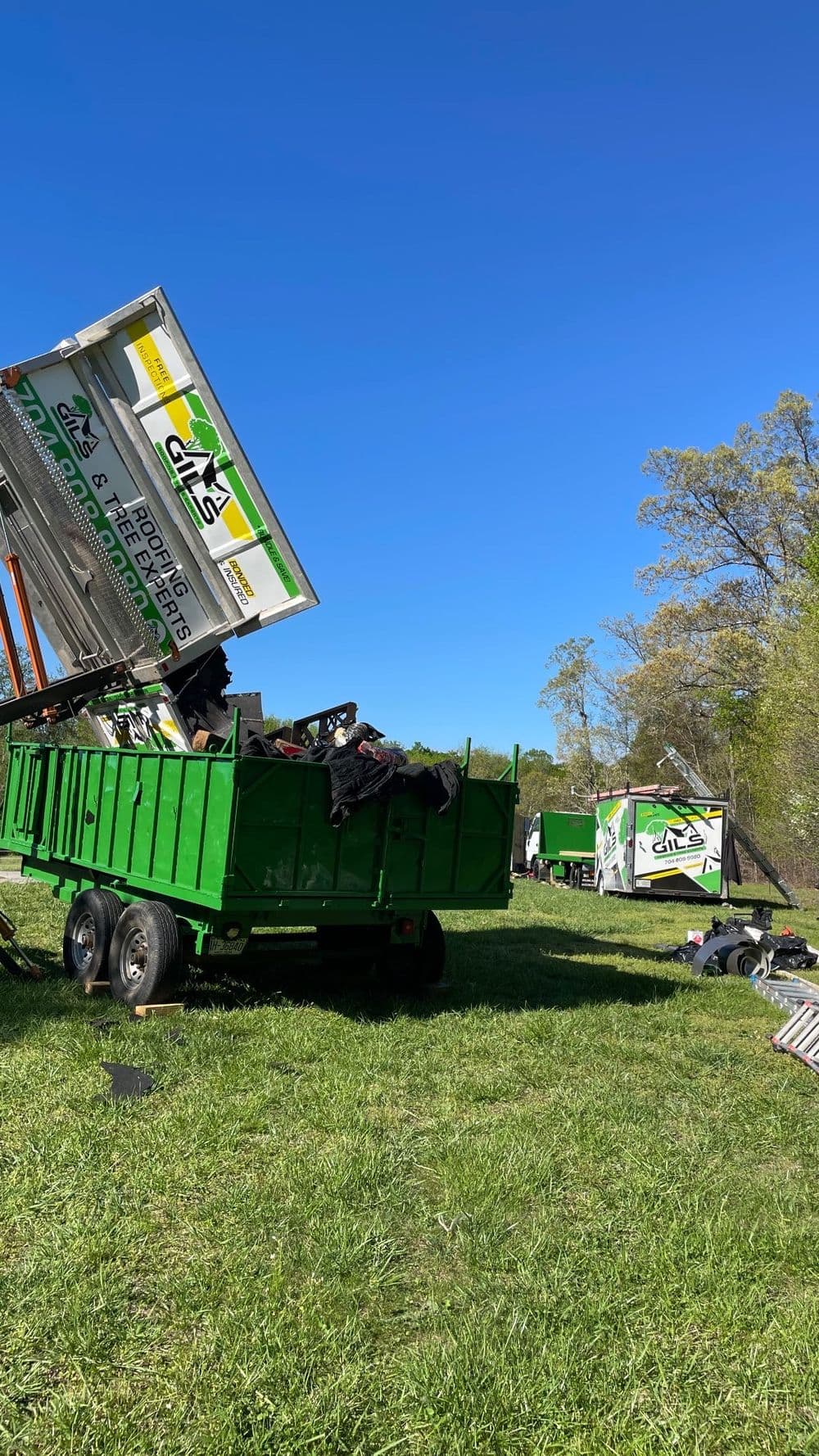 Green waste removal trucks unloading materials in a sunny outdoor setting.